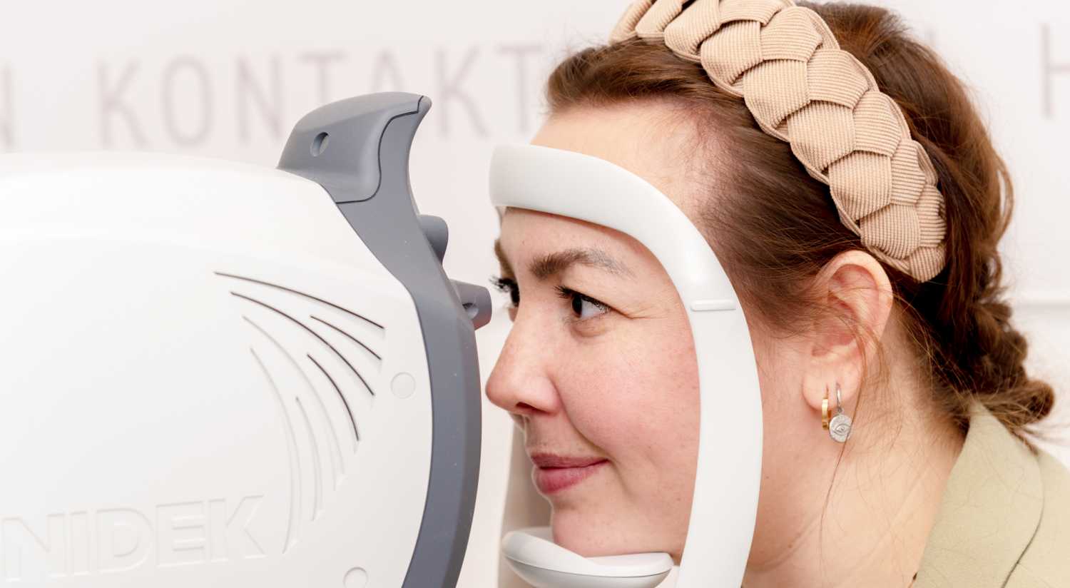 Eine Frau schaut erwartungsvoll in ein Messgerät zur Augenvermessung.